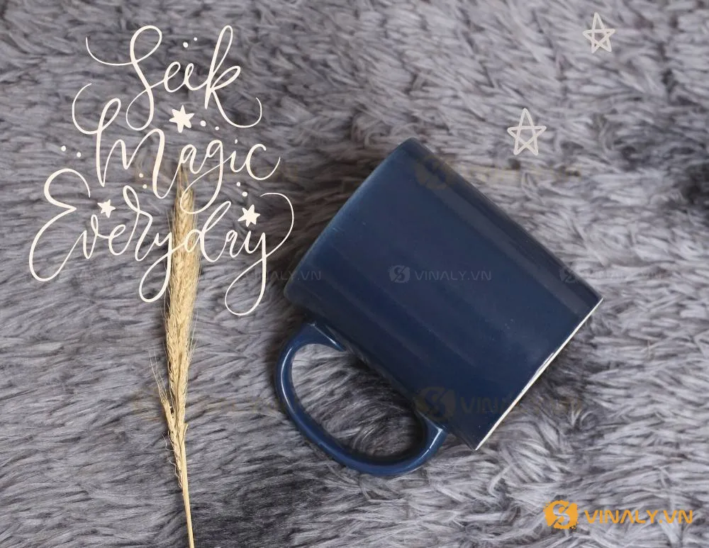 LY SỨ TRỤ MÀU XANH CỬU LONG - cốc màu xanh 7 Ly sứ trụ màu xanh cửu long in logo đặt nghiêng trên nền lông xám, cạnh cành cây khô và chữ trang trí 'Seek Magic Everyday'.
