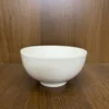 Hình ảnh chén sứ trắng trơn, kiểu dáng đơn giản, đặt trên mặt bàn gỗ nâu, phù hợp làm quà tặng doanh nghiệp với dịch vụ in
