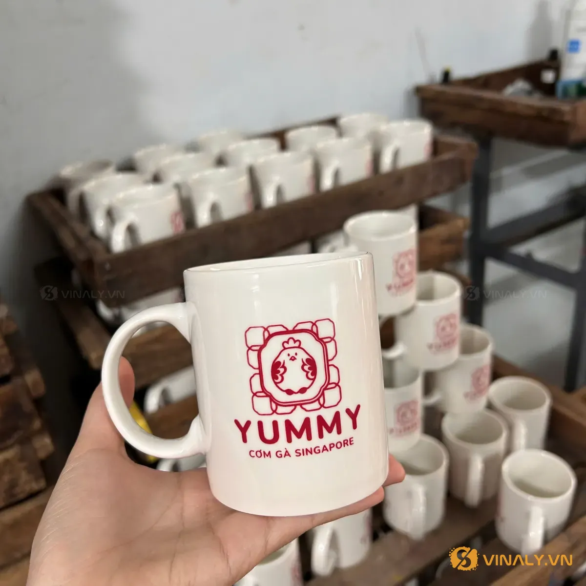 Ly sứ in logo thương hiệu cơm gà xếp hàng loạt trên kệ xưởng - quà tặng khuyến mãi số lượng lớn